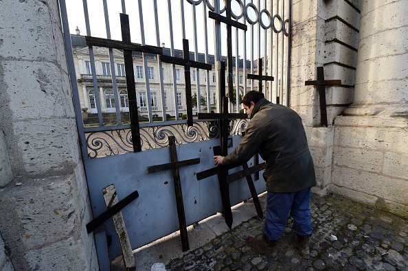 Un agriculteur place des croix de bois devant l'entrée de la préfecture lors d'une manifestation à Agen, le 23 janvier 2017, alertant sur les centaines de suicides d'agriculteurs français en 2016. (MEHDI FEDOUACH/AFP via Getty Images)