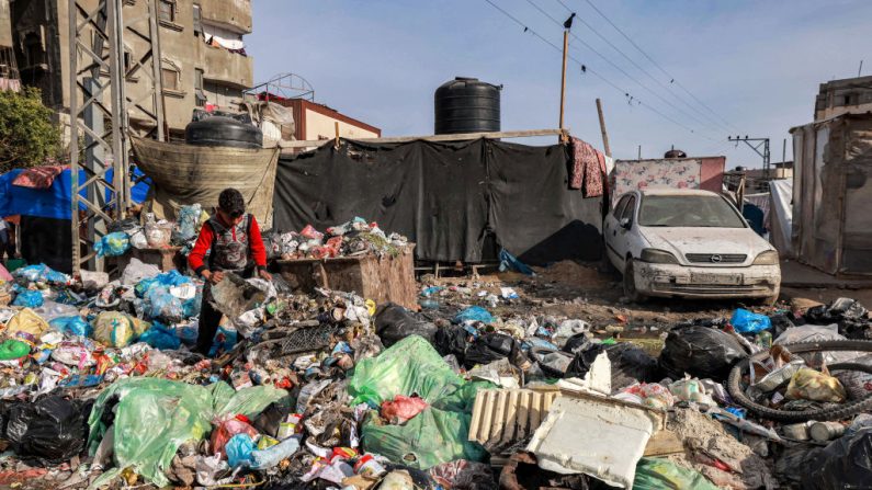 Un garçon fouille les ordures dans une décharge près de l'un des camps hébergeant des Palestiniens déplacés par la guerre à Rafah, dans le sud de la bande de Gaza, le 12 février 2024. (Photo MOHAMMED ABED/AFP via Getty Images)