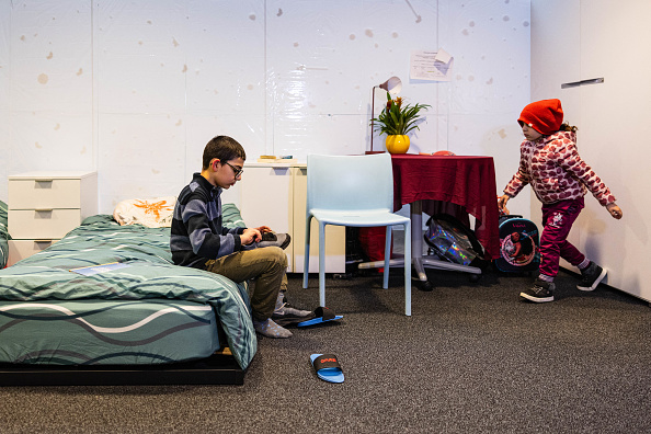 Gor (à g.), un garçon arménien sans-abri de 10 ans, met ses pantoufles dans la chambre de sa famille, dans des locaux d'entreprise. (Photo SAMEER AL-DOUMY/AFP via Getty Images)