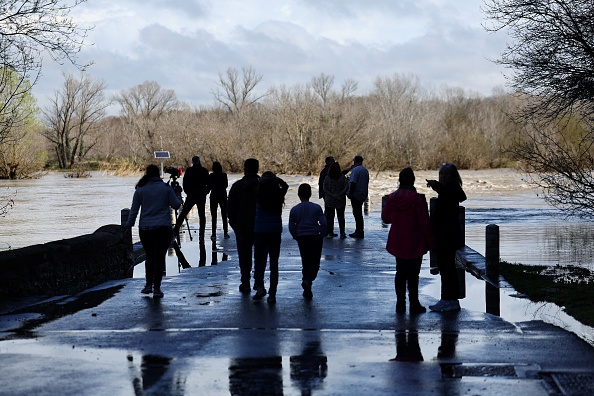 Des personnes regardent un pont submergé par la rivière Gard en crue à Dions, le 10 mars 2024. (Photo CLEMENT MAHOUDEAU/AFP via Getty Images)