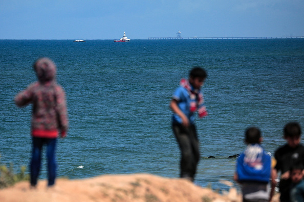 Des enfants palestiniens se rassemblent sur la plage alors que le navire Open Arms, parti de Larnaca à Chypre et transportant de l'aide humanitaire, approche de la côte de la ville de Gaza, le 15 mars 2024. (Photo AFP via Getty Images)