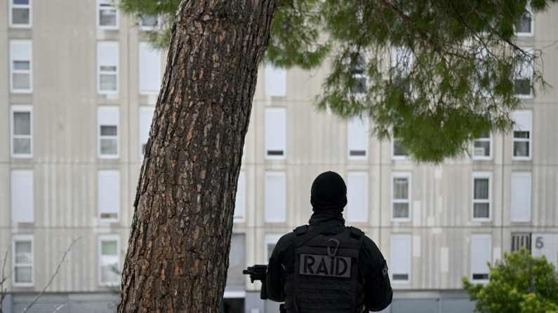 Un policier  en position avant la visite du président français Emmanuel Macron dans le quartier de La Castellane à Marseille, le 19 mars 2024. Emmanuel Macron a promis le 19 mars une "opération sans précédent" contre le trafic de drogue à Marseille lors d'une visite surprise dans la ville portuaire du sud en proie à des meurtres commis par des gangs.(NICOLAS TUCAT/AFP via Getty Images)