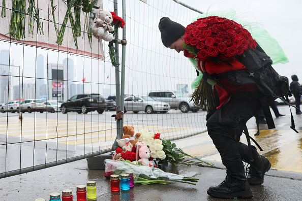 Une femme dépose des fleurs à un mémorial improvisé devant l'hôtel de ville de Crocus, un jour après une attaque armée à Krasnogorsk, à l'extérieur de Moscou, le 23 mars 2024. (Photo STRINGER/AFP via Getty Images)