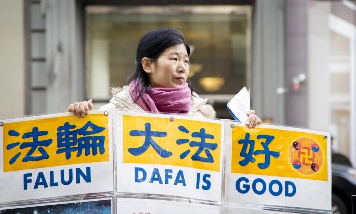 Wang Huijuan, devant l'Empire State Building à New York, le 12 janvier 2017, tient un présentoir pour aider les touristes chinois à comprendre les faits sur la persécution du Falun Gong en Chine. (Samira Bouaou/Epoch Times)