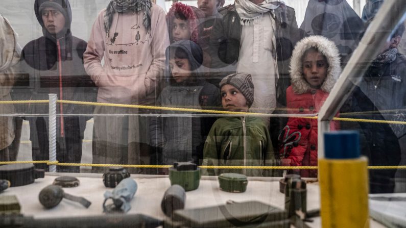 Des enfants réfugiés afghans accompagnés de leurs aînés regardent des types de mines terrestres et d'autres engins explosifs dans le cadre d'un programme d'information sur la sécurité au camp du Haut Commissariat des Nations Unies pour les réfugiés (HCR) à la périphérie de Kaboul, le 9 janvier 2024, après leur expulsion du Pakistan. (Photo WAKIL KOHSAR/AFP via Getty Images)