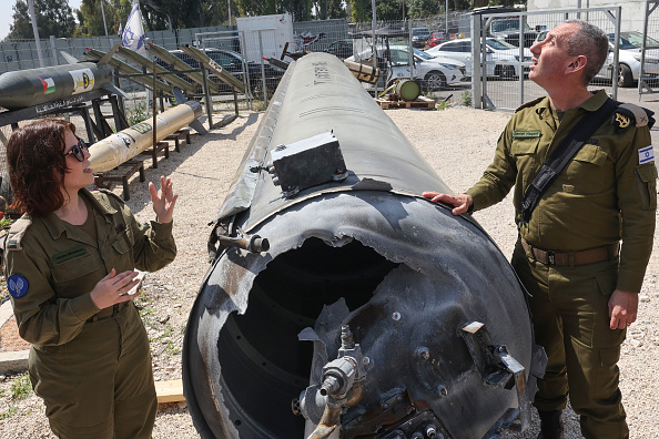 Le porte-parole militaire israélien, le contre-amiral Daniel Hagari, et son adjointe Masha Michelson posent à côté d'un missile balistique iranien tombé en Israël ce week-end, lors d'une visite des médias à la base militaire de Julis, près de la ville de Kiryat Malachi, dans le sud d'Israël, le 16 avril 2024. (Photo GIL COHEN-MAGEN/AFP via Getty Images)