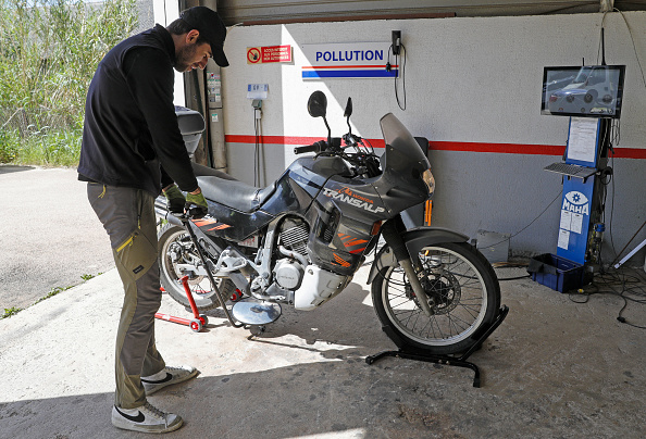 Un employé effectue un contrôle visuel sous une moto lors d'une inspection de sécurité routière dans un centre Autovision à Ajaccio,  le 16 avril 2024.  (PASCAL POCHARD-CASABIANCA/AFP via Getty Images)