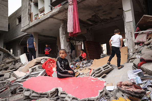 Des enfants palestiniens marchent au milieu des débris d'une maison détruite par un bombardement israélien à Rafah. (Photo AFP via Getty Images)