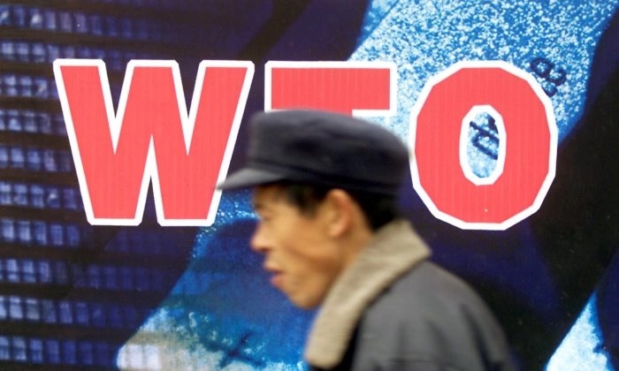 Un Chinois passe devant un panneau d'affichage promouvant l'adhésion du pays à l'Organisation mondiale du commerce (OMC ou WTO en français), à Pékin, le 10 décembre 2001. (Goh Chai Hin/AFP/Getty Images)