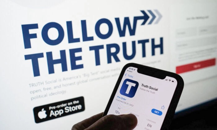 Sur un smartphone, une personne consulte l'application « Truth Social » - appartenant à Trump Media & Technology Group - avec, en arrière plan, le site web de l'application affiché sur un écran d'ordinateur, à Los Angeles, Californie, le 20 octobre 2021. (Chris Delmas/AFP via Getty Images)