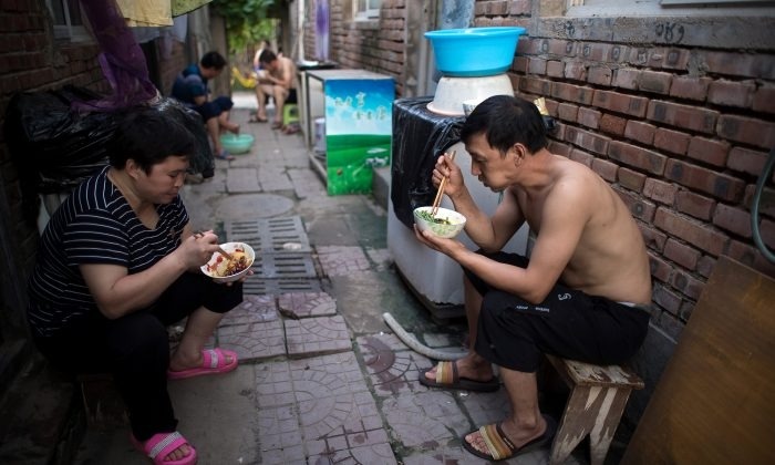 Des personnes dînent dans les rues d'un village de migrants à la périphérie de Pékin, le 17 août 2017. (Nicolas Asfouri/AFP/Getty Images)