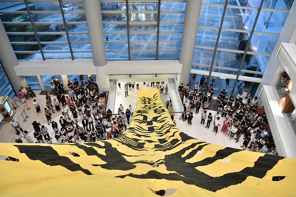 Une grande bannière est affichée après avoir été déployée alors que des étudiants se rassemblent dans un centre commercial du quartier de Lok Fu à Hong Kong, le 23 septembre 2019, pour chanter une chanson de protestation récemment écrite, intitulée « Glory to Hong Kong ». (Photo ANTHONY WALLACE/AFP via Getty Images)