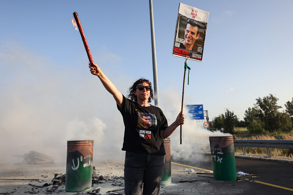 Une femme tient une affiche portant l'image de Dror Or, otage israélien de 43 ans, lors d'une manifestation appelant à leur libération le 19 avril 2024. (Photo AHMAD GHARABLI/AFP via Getty Images)