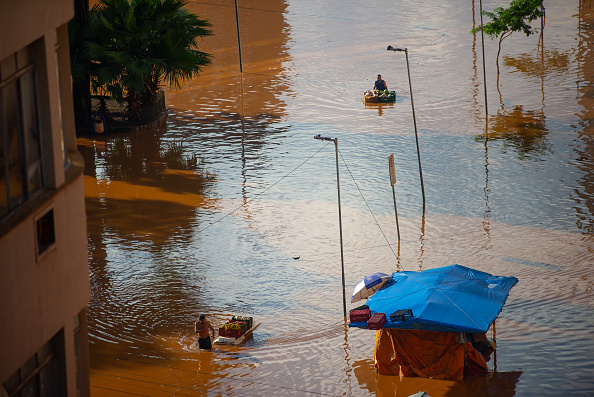 Des personnes transportent des légumes et des fruits dans une rue inondée après le débordement de la rivière Guaiba au centre-ville le 5 mai 2024 à Porto Alegre, Brésil. (Photo Matheus Piccini/Getty Images)