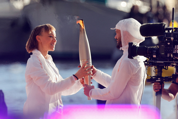 Le chanteur Jul a reçu la torche olympique des mains de la championne paralympique d'athlétisme Nantenin Keïta, fille du musicien malien Salif Keïta, qui l'avait elle-même reçue de Florent Manaudou, champion olympique du 50 m nage libre en 2012 à Londres. (Photo LUDOVIC MARIN/POOL/AFP via Getty Images)