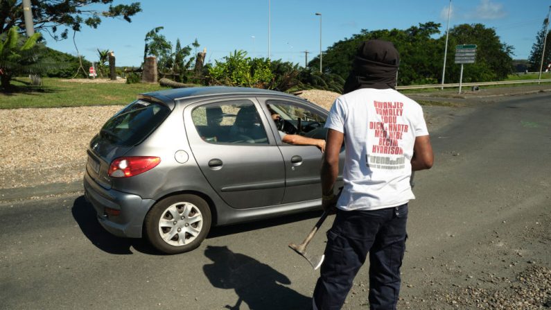 Un homme armé d'une petite machette contrôle l'accès à un quartier de Nouméa, en Nouvelle-Calédonie, le 24 mai 2024. (Photo THEO ROUBY/AFP via Getty Images)