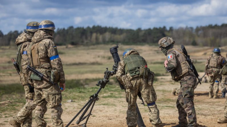 Un instructeur de l'armée française (à droite) vérifie le mortier avant que les soldats ukrainiens ne le tirent lors d'un entraînement militaire mené avec des militaires français, dans un complexe d'entraînement militaire situé dans un lieu non divulgué en Pologne, le 4 avril 2024. (WOJTEK RADWANSKI/AFP via Getty Images)