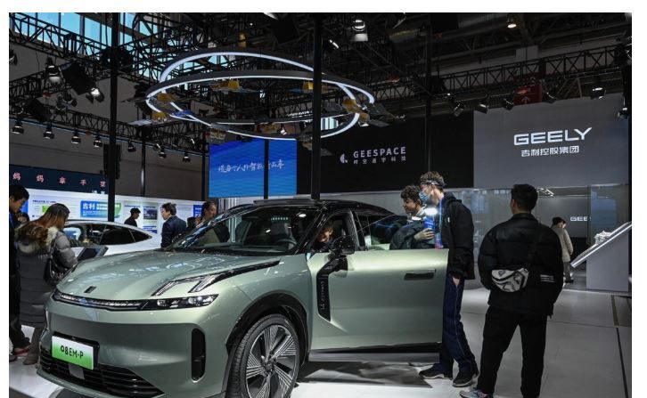 Des visiteurs essaient une voiture électrique sur le stand du fabricant automobile chinois Geely lors de l'Exposition internationale de la chaîne d'approvisionnement chinoise à Pékin, le 1er décembre 2023. (Jade Gao/AFP via Getty Images)