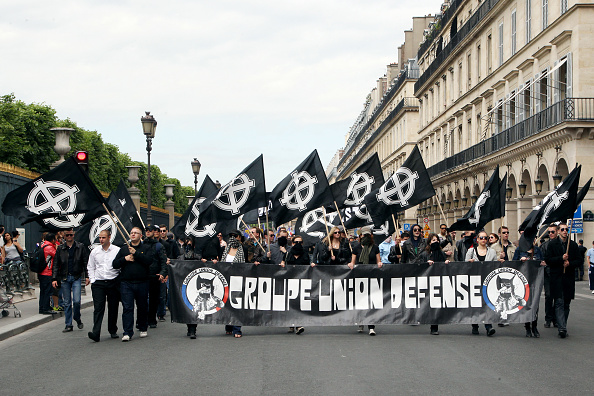 Des membres du GUD tiennent une bannière et des drapeaux avec le symbole nationaliste de la croix celtique. (THOMAS SAMSON/AFP via Getty Images)