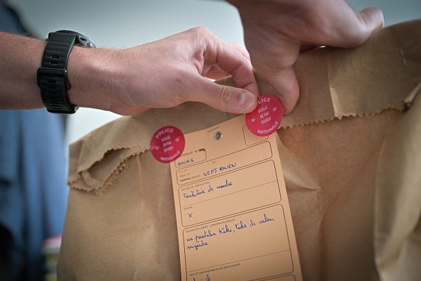 Un officier de police appose des autocollants sur un sac de preuves scellé lors d'un exercice au Service Interdépartemental de la Police Judiciaire (SIPJ) à Rouen, le 13 juin 2024. (Photo LOU BENOIST/AFP via Getty Images)