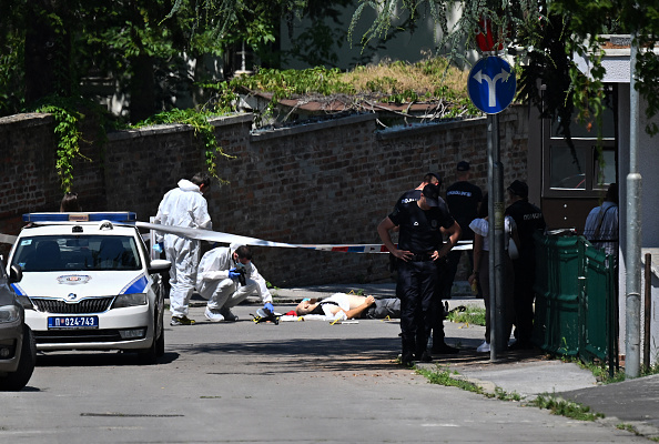 Des agents de la police scientifique inspectent un corps gisant sur la route à côté de l'ambassade d'Israël à Belgrade, le 29 juin 2024.  (OLIVER BUNIC/AFP via Getty Images)