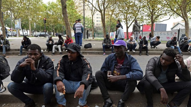 Des migrants mangent de la nourriture distribuée par l'association Utopia 56 dans une rue de Paris, le 11 octobre 2017. (Crédit photo CHRISTOPHE ARCHAMBAULT/AFP via Getty Images)