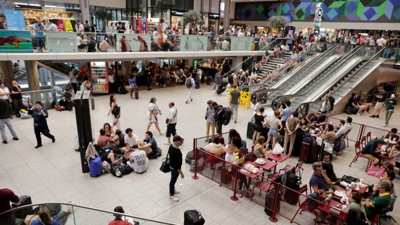 Des passagers attendent le départ de leur train à la gare Montparnasse à Paris, le 26 juillet 2024, alors que le réseau ferroviaire à grande vitesse français a été touché par des actes de malveillance perturbant le système de transport quelques heures avant la cérémonie d'ouverture des Jeux olympiques de Paris 2024. (THIBAUD MORITZ/AFP via Getty Images)