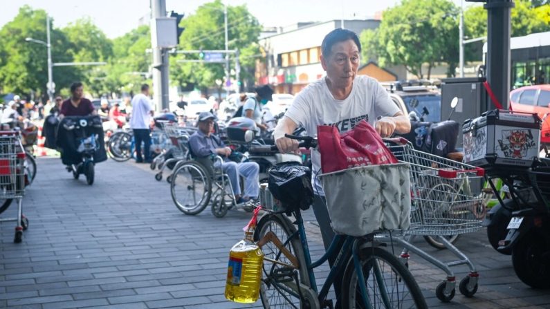 Un homme à vélo transporte une bouteille en plastique d'huile de cuisine à la sortie d'un supermarché à Pékin, le 12 juin 2024. (Wang Zhao/AFP via Getty Images)