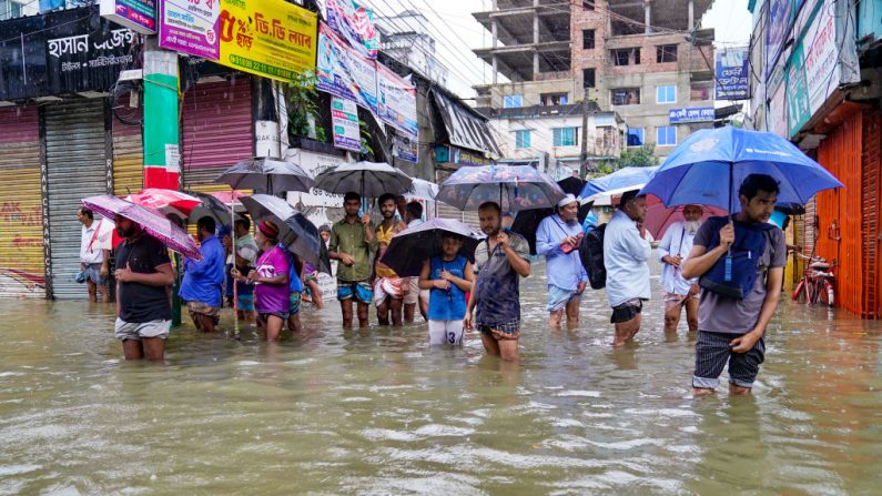 Des personnes portant des parapluies pataugent dans une rue inondée par la pluie à Feni, le 22 août 2024. (AFP via Getty Images)