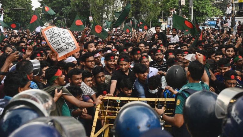 Des étudiants activistes poussent des barricades dressées par la police lors d'un rassemblement de protestation avant de soumettre leur mémorandum au président du pays sur la réforme des quotas pour les emplois de la fonction publique, à Dacca, le 14 juillet 2024. (MUNIR UZ ZAMAN/AFP via Getty Images)