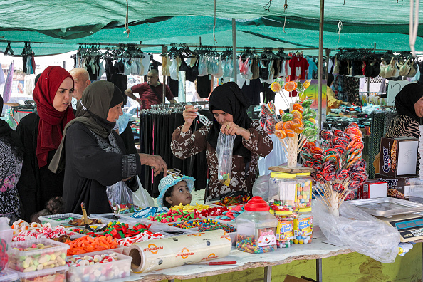 Des femmes achètent des bonbons sur un marché en plein air dans la ville bédouine de Rahat, dans le sud de la région du Néguev, le 8 juin 2021. Les Bédouins appartiennent à la communauté des Arabes israéliens, descendants des Palestiniens restés sur leurs terres lors de la création d'Israël en 1948, et vivent en majorité dans la région aride du Néguev.  (Photo HAZEM BADER/AFP via Getty Images)