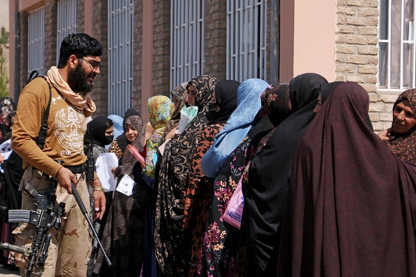 Un agent de sécurité taliban au côté des femmes devant le bureau des passeports à Herat, Afghanistan, le 26 août 2023 (MOHSEN KARIMI/AFP via Getty Images)