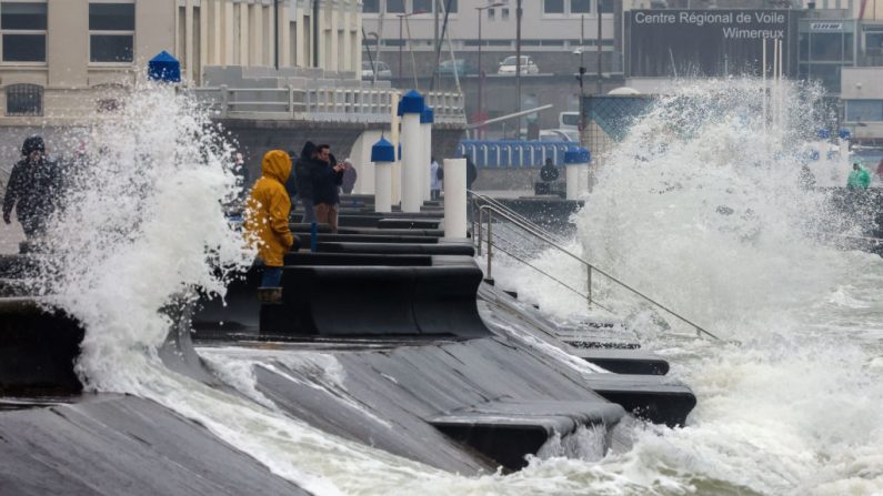 Des gens se promènent alors que de grosses vagues déferlent sur le rivage à Wimereux, le 11 mars 2024, lors des marées d'équinoxe. (Crédit photo DENIS CHARLET/AFP via Getty Images)