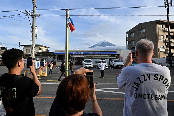 Des touristes prenant des photos du mont Fuji en face d'une supérette dans la ville de Fujikawaguchiko, préfecture de Yamanashi. (KAZUHIRO NOGI/AFP via Getty Images)