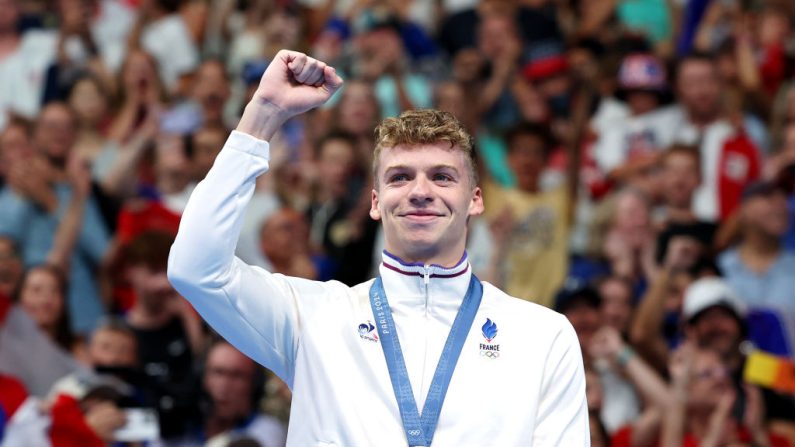 Le médaillé d'or Leon Marchand de l'équipe de France célèbre sur le podium pendant la cérémonie de remise des médailles de natation après la finale du 400m quatre nages individuel masculin lors de la deuxième journée des Jeux Olympiques Paris 2024 à La Défense Arena, le 28 juillet 2024 à Nanterre. (Crédit photo Quinn Rooney/Getty Images)