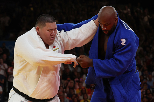 Le Japonais Tatsuru Saito et le Français Teddy Riner (bleu) participent au combat pour la médaille d'or de l'équipe mixte de judo entre le Japon et la France aux Jeux olympiques de Paris 2024 dans l'arène du Champ-de-Mars, à Paris, le 3 août 2024.  (JACK GUEZ/AFP via Getty Images)