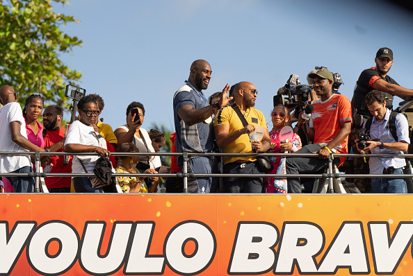 Teddy Riner, médaillé d'or, salue la foule à bord d'un bus à impériale alors qu'il arrive à Pointe-a-Pitre sur son île natale, en Guadeloupe. (BRIAN NOCANDY/AFP via Getty Images)