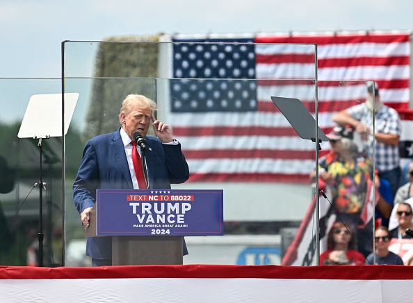 L'ancien président américain et candidat républicain à la présidence Donald Trump s'exprime derrière une vitre pare-balles lors d'un meeting de campagne au North Carolina Aviation Museum & Hall of Fame à Asheboro, en Caroline du Nord, le 21 août 2024. (Photo PETER ZAY/AFP via Getty Images)