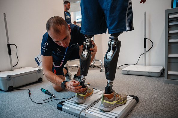 Un technicien ajuste les jambes prothétiques du para-athlète français Alexis Sanchez au centre de réparation de prothèses Ottobock dans le village des athlètes paralympiques à Saint-Denis le 24 août 2024, avant les Jeux Paralympiques de Paris 2024. Le centre fournit gratuitement des ajustements et des réparations de prothèses, d'orthèses et d'équipements pour les athlètes et les participants aux Jeux paralympiques de Paris 2024.  (Photo DIMITAR DILKOFF/AFP via Getty Images)
