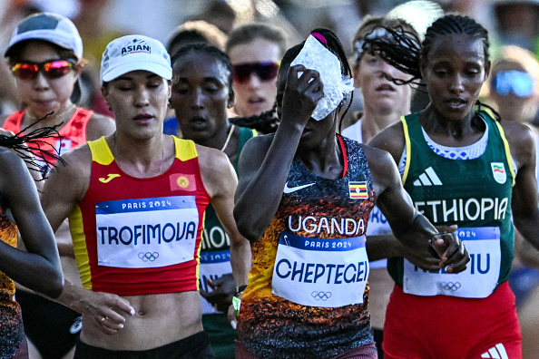 L'Ougandaise Rebecca Cheptegei (au c.) applique un sac de glace sur sa tête alors qu'elle participe au marathon féminin de l'épreuve d'athlétisme des Jeux olympiques de Paris 2024, le 11 août 2024. (Photo KIRILL KUDRYAVTSEV/AFP via Getty Images)