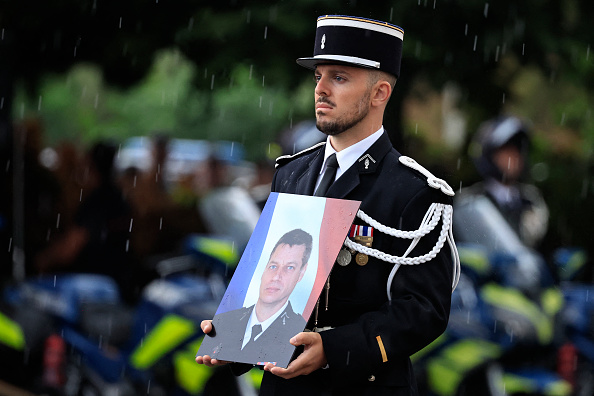 Un gendarme français tient la photo du gendarme Éric Comyn, mortellement renversé lors d'un contrôle routier, lors d'une cérémonie d'hommage à Nice le 2 septembre 2024. (Photo VALERY HACHE/AFP via Getty Images)