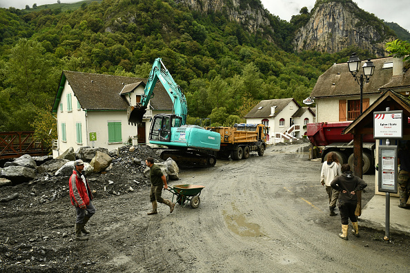 Des habitants nettoient une rue d'Etsaut après les inondations causées par les eaux du Gave d'Aspe suite à de fortes pluies, sud-ouest de la France, le 8 septembre 2024. (GAIZKA IROZ/AFP via Getty Images)