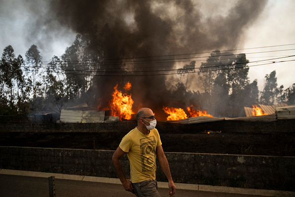 Un habitant passe devant un entrepôt en flammes lors d'un incendie de forêt dans le village d'Arrancada, Agueda à Aveiro, le 17 septembre 2024. (PATRICIA DE MELO MOREIRA/AFP via Getty Images)