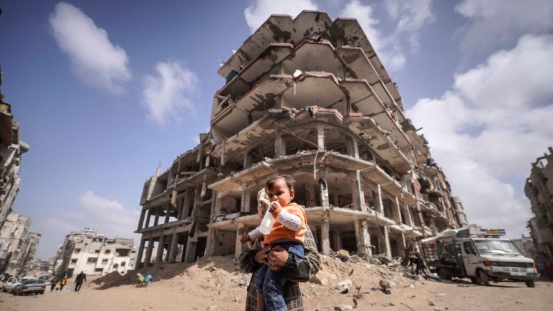 Une femme palestinienne et un enfant se tiennent devant les décombres des maisons détruites par les bombardements israéliens à Khan Yunis, dans le sud de la bande de Gaza, le 6 mars 2024, dans le cadre du conflit entre Israël et le mouvement Hamas. (-/AFP via Getty Images)