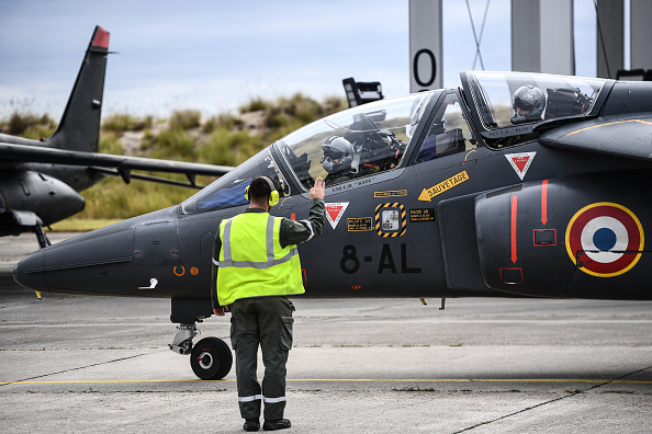 Un stagiaire ukrainien (au c.) et un instructeur militaire français (à dr.) se dirigent vers la piste de décollage pour un vol à bord d'un avion de chasse Alpha Jet, sur une base aérienne de l'armée française, le 14 juin 2024. (CHRISTOPHE ARCHAMBAULT/AFP via Getty Images)