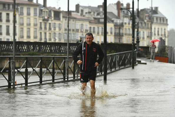 Un piéton court dans une rue inondée lors du débordement de la Nive à Bayonne, dans le sud-ouest de la France, le 17 octobre 2024. (GAIZKA IROZ/AFP via Getty Images)