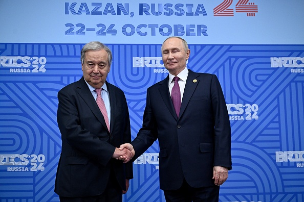 Le Président russe Vladimir Poutine (à dr.) salue le secrétaire général de l'Organisation des Nations unies (ONU), Antonio Guterres, lors de leur rencontre bilatérale en marge du sommet des BRICS à Kazan, le 24 octobre 2024. (Photo ALEXANDER NEMENOV/POOL/AFP via Getty Images)