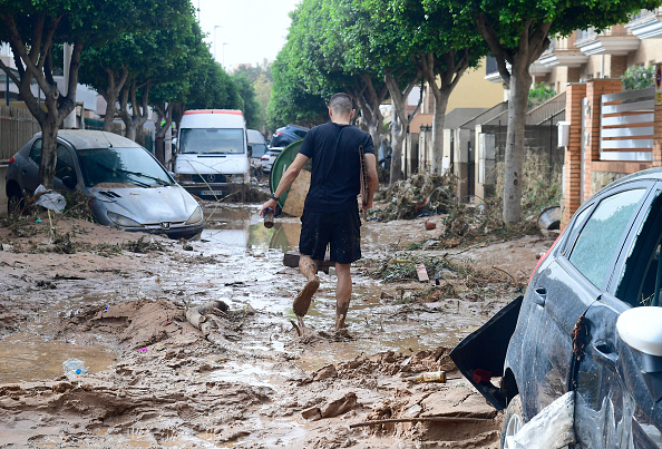 Un homme marche dans une rue couverte de boue dans une zone inondée à Picanya, près de Valence, en Espagne. (JOSE JORDAN/AFP via Getty Images)