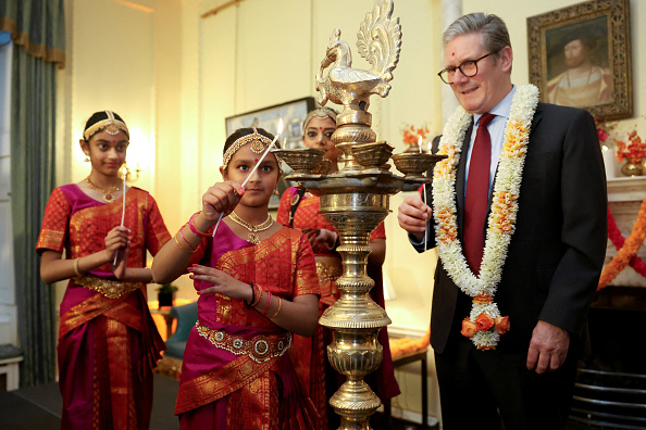 Le Premier ministre britannique Keir Starmer et des membres de la Arunima Kumar Dance Company tiennent des bougies pour allumer une lampe pour célébrer le Diwali, le 29 octobre 2024 à Londres, en Angleterre. (Mina Kim - WPA Pool/Getty Images)