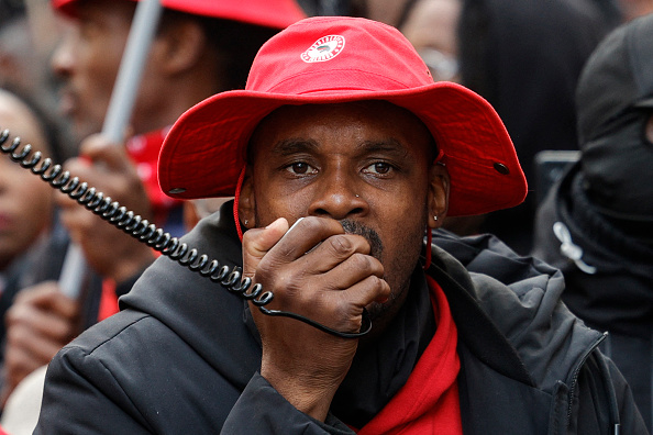 Rodrigue Petitot s'exprime dans un mégaphone lors d'une marche contre la vie chère, Place Denfert-Rochereau à Paris, le 3 novembre 2024. (GEOFFROY VAN DER HASSELT/AFP via Getty Images)